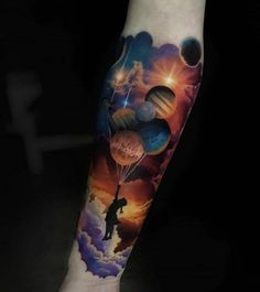 a man's arm with an image of planets and a person holding a balloon in the sky