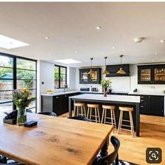 a kitchen with black cabinets and counter tops next to a dining room table in front of an open floor plan