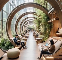 people are sitting in chairs and working on laptops inside an indoor area with plants