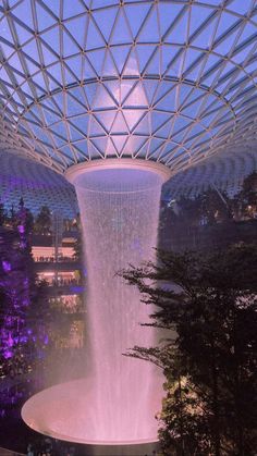 an indoor waterfall is lit up at night