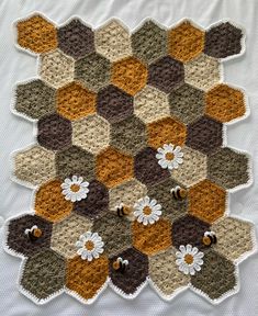 a crocheted hexagonal pattern with flowers on the center and two bees in the middle