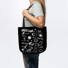 a woman carrying a black tote bag with drawings on it