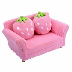 a pink couch with two stuffed strawberries on it's back and one sitting on the other side