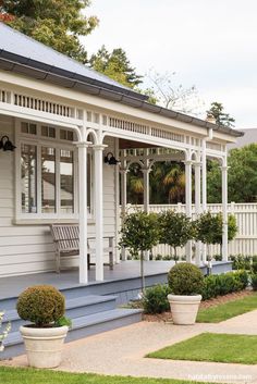 a white house with two large planters on the front lawn and an attached porch