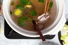 a bowl of soup with chopsticks in it and some vegetables on the side