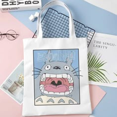 This tote bag features the iconic My Neighbor Totoro character yawning. Carry your books, groceries, and everyday essentials. It features a high-quality print that does not fade. It has one main pocket to place all the items in and can easily open to take anything out. Ideal for a Studio Ghibli fan! Size: 34 cm x 38 cm Material: cotton Totoro Tote Bag, Big Palace, My Neighbor Totoro Characters, Totoro Print, Totoro Characters, Cute Totoro, Diy Tote Bag Design, Anime Tote Bag, Handpainted Tote Bags