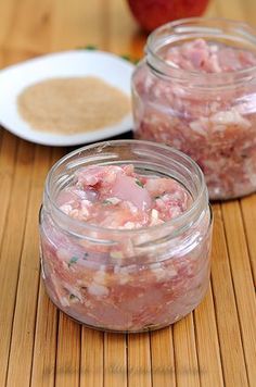 two jars filled with food sitting on top of a wooden table next to an apple