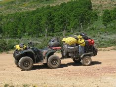 two atvs loaded with luggage on a dirt road