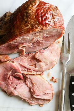 the ham is cut up and ready to be eaten with a knife and fork next to it