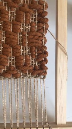 a close up of a weaving machine with brown and white yarn on the back side