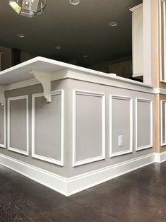 an empty kitchen with white cabinets and wood flooring in the middle of the room