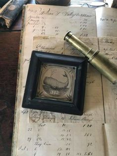 an old book with writing on it and a pen laying next to it, sitting on top of a table