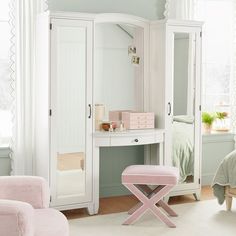 a white dressing table with a pink stool and mirror in the corner next to it