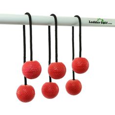 four red balls are hanging from a white pole with black string and the words ladder golf written on it