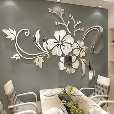 a dining room table with white chairs and flowers on the wall behind it is decorated in silver