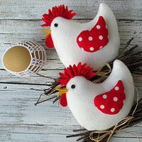 two white chickens with red polka dots sitting on top of some twigs and eggs in front of them