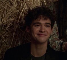 the young man is smiling in front of hay