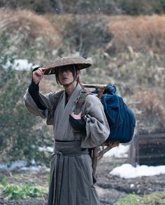 a man wearing a hat and carrying a bag on his back while walking in the snow