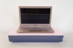 an open laptop computer sitting on top of a blue and green box with a white background