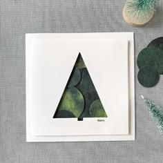 a card with a green triangle on it next to some leaves and a potted plant