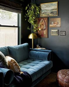 a living room with a blue couch and pictures on the wall above it, along with a gold lamp