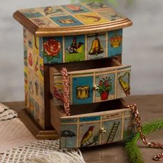 a wooden jewelry box sitting on top of a table next to a christmas tree branch