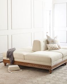 a white couch sitting on top of a rug in a living room next to a window