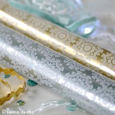 two gold and silver decorative items on a white table cloth with blue flowers in the background