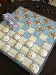 a blue and white checkerboard board with sand dollars on it, sitting on a table