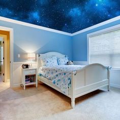 a bedroom with blue walls and a ceiling that has stars painted on the ceiling above it