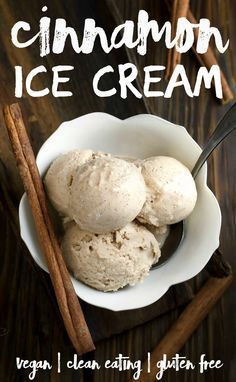 two scoops of cinnamon ice cream in a white bowl with cinnamon sticks on the side