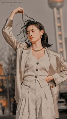 a woman standing in front of a building with her hands on her head and wearing a suit