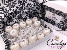 a box filled with cake pops covered in white frosting and black damask paper