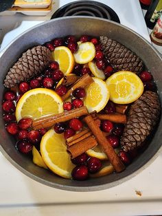 a pan filled with lemons, cranberries and cinnamon sticks