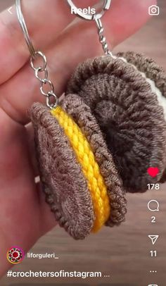 a hand holding a brown and yellow stuffed animal keychain