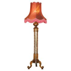 a lamp that is on top of a wooden stand with a pink shade over it