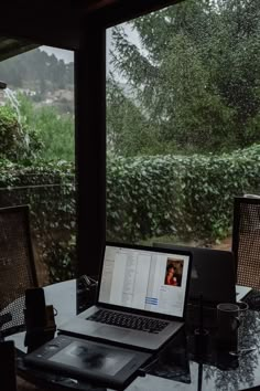 an open laptop computer sitting on top of a glass table next to a coffee cup