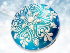 a blue ball with white designs on it and snow flakes in the back ground