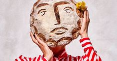 a person holding a loaf of bread in front of their face with a flower on it