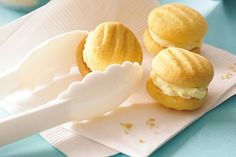 three small pastries sitting on top of a white paper towel next to a plastic spoon