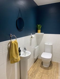 a white toilet sitting next to a sink in a bathroom under a round mirror on the wall