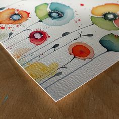 a close up of a piece of paper on a wooden surface with flowers painted on it