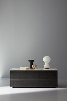 a white vase sitting on top of a wooden table next to a black and white object