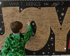 a young boy writing on a bulletin board that says joy and what brings you joy