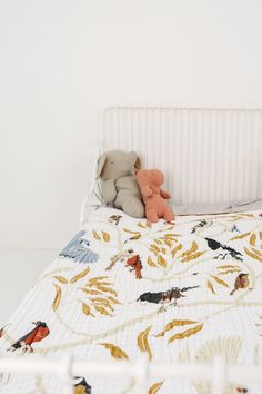 a teddy bear sitting on top of a bed next to a stuffed animal in a crib