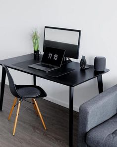 a laptop computer sitting on top of a wooden desk next to a gray couch in a living room