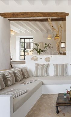 a living room filled with white furniture and lots of pillows