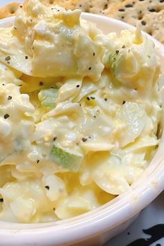 a white bowl filled with pasta and cheese next to crackers on a table top