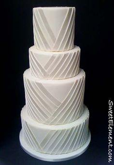 a three tiered white cake sitting on top of a table next to a black background