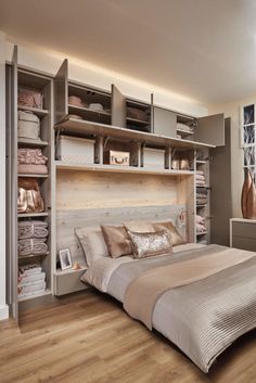 a large bed sitting under a window next to a wooden shelf filled with folded towels